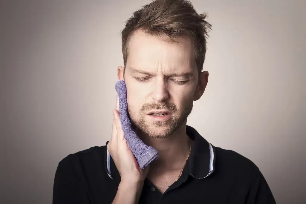Man holding towel over his jaw and facial muscles