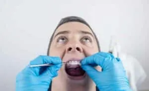 Dentist performing oral examination with tools.
