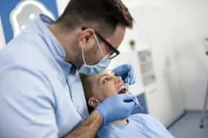 Dentist examining patient’s teeth during appointment.