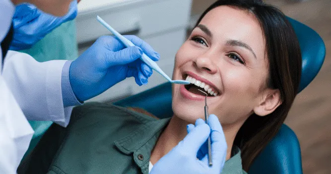 Dentist performing a dental cleaning on a smiling patient.