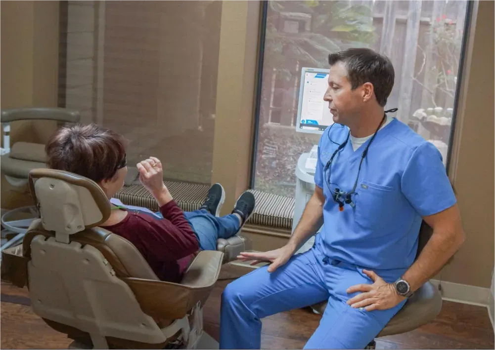 Dentist consulting patient in examination room.