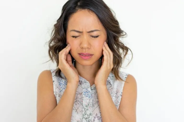 Woman holding jaw with a pained expression.